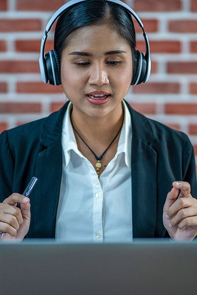 woman with headphones at a laptop doing a video call