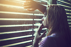 woman looking out the window in a dark room