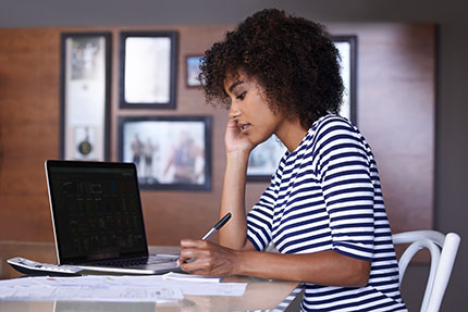 woman sitting at a table writing while on the phone