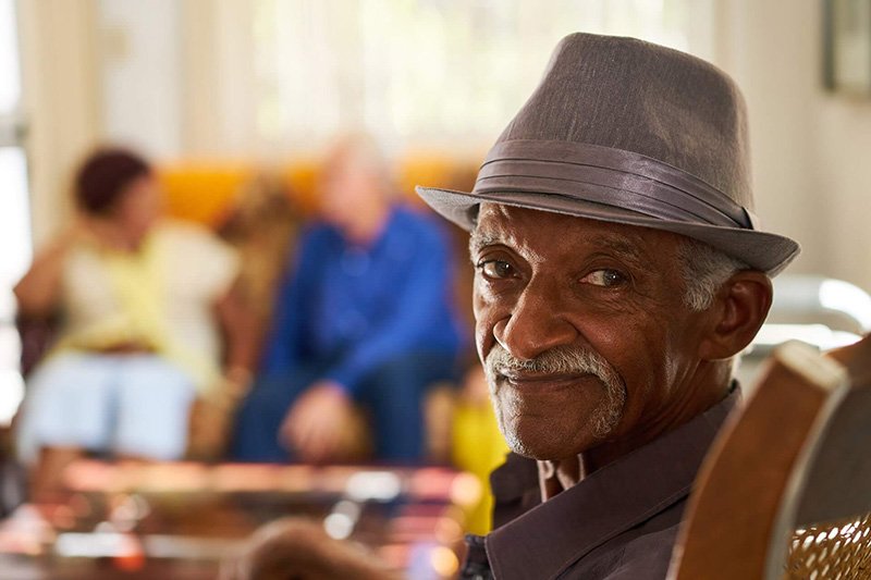 older gentleman in a hat looking at the camera