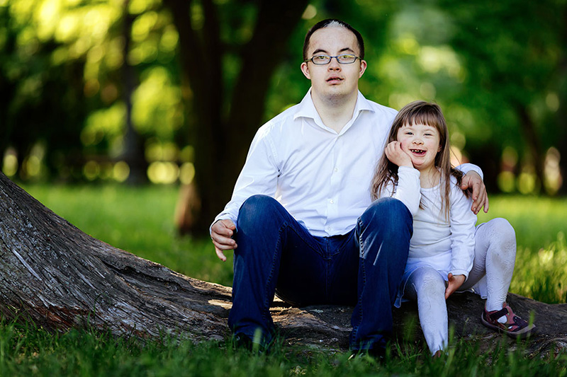 Teenage boy and young girl sitting on a tree stump