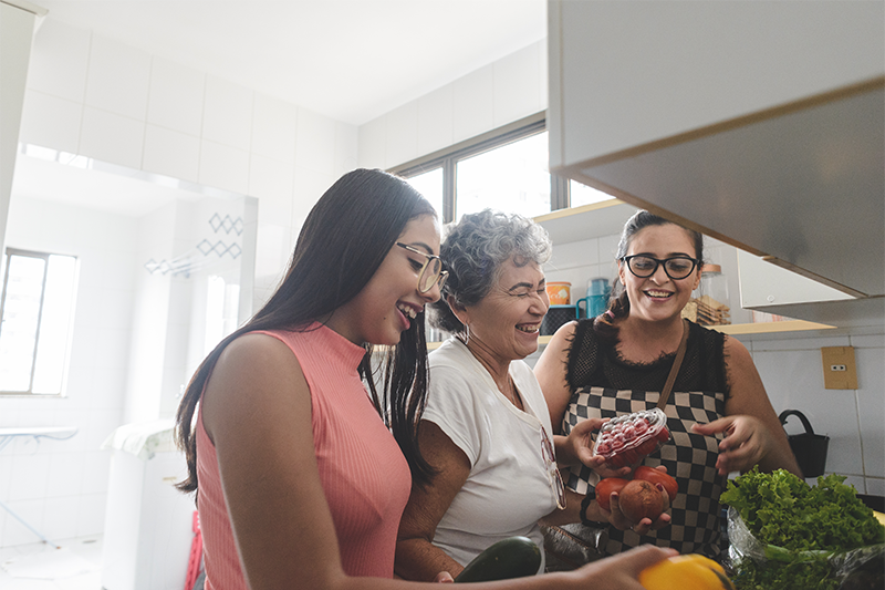 mother and two daughters in the kitchen with groceries laughing