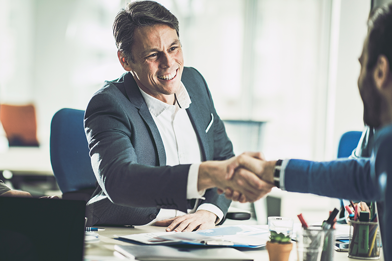 two men sitting down shaking hands