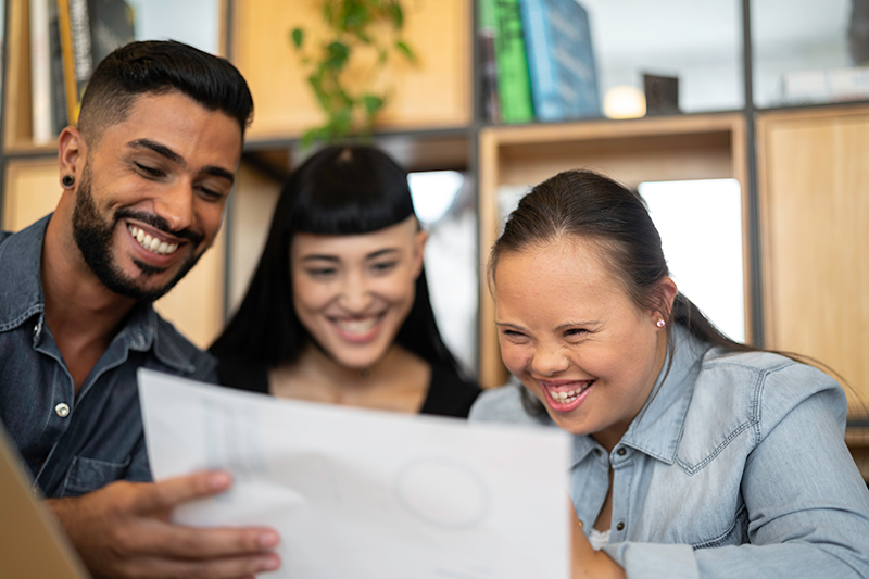 man and two women sitting at table laughing looking at piece of paper