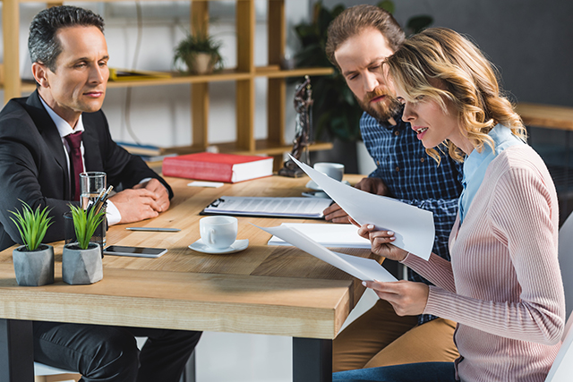 couple sitting at a table across from a lawyer looking at paperwork