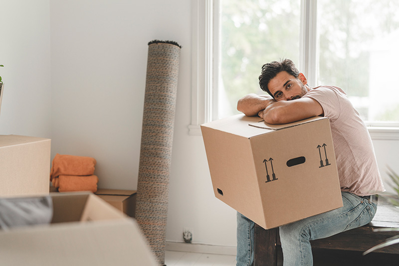 man sitting down with a moving box in his lap