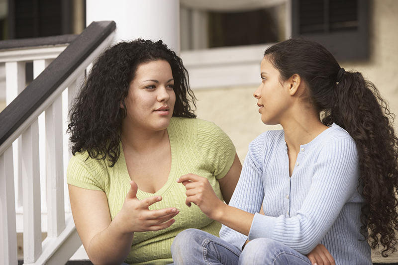 two women sitting on steps and talking