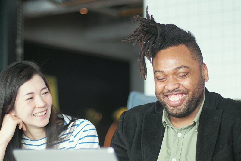 man and woman sitting at computer smiling