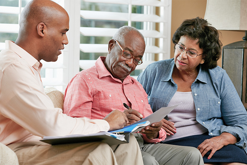 older gentleman and woman filling out forms with the help of a younger gentleman