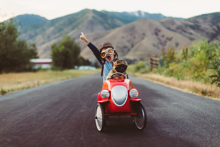 young boy and dog riding in a toy car