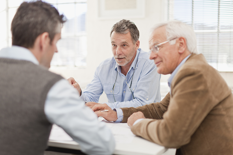 three men talking at a table